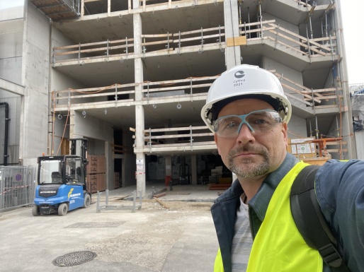 Ein Selfie von Rudi Pfaffenlehner mit Bauhelm vor einem Rohbau.